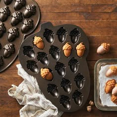 two pans filled with cookies on top of a wooden table next to baking utensils