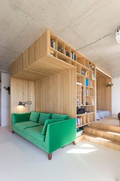 a green couch sitting in front of a bookshelf next to a stair case