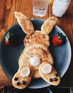 a plate topped with pancakes covered in toppings next to a strawberries and milk