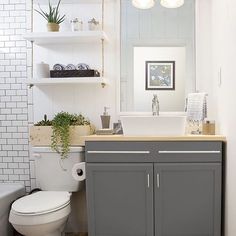 a white toilet sitting next to a sink in a bathroom under a mirror and lights