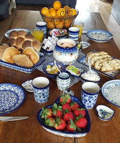 a wooden table topped with blue and white dishes filled with food next to oranges