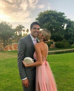 a man and woman in formal wear standing next to each other on a grass field