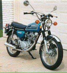 a blue and black motorcycle parked in front of a garage with a white door behind it