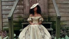 a woman in a dress and hat sitting on a bench