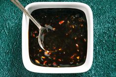 a white bowl filled with soup on top of a green carpeted floor next to a spoon