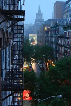 a city street filled with lots of traffic next to tall buildings and trees in the distance