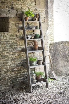 a ladder leaning against a brick wall with potted plants on the top and bottom