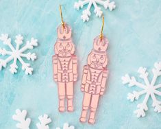 two pink wooden toy figures sitting next to snowflakes