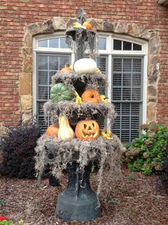 a fountain with pumpkins and gourds on it in front of a brick building