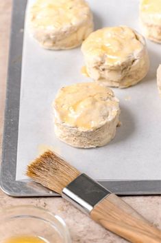 some biscuits are sitting on a baking sheet with a brush