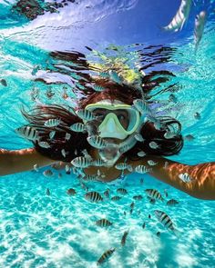 a woman swimming in the ocean with her mask on and snorkels around her