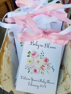 a baby in bloom gift box with ribbon and tags on the front, sitting on a wooden table