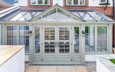 an orangery in front of a brick building with glass doors and windows on each side