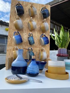 blue and yellow vases on display in front of a wooden board with hanging hooks