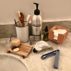 a bathroom counter with soap, toothbrushes and other items sitting on top of it