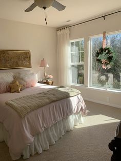 a bedroom with a ceiling fan, bed and two windows in front of the room