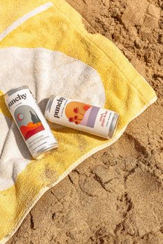 two sunscreens are laying on a towel in the sand