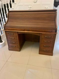 a wooden desk sitting on top of a tiled floor next to a bannister