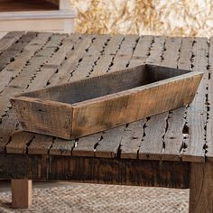 a wooden tray sitting on top of a table next to a rug and window sill