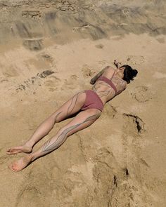 a woman laying on top of a sandy beach