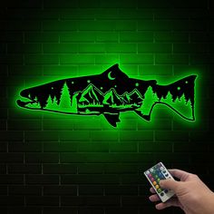 a person holding a remote control in front of a wall with a fish on it