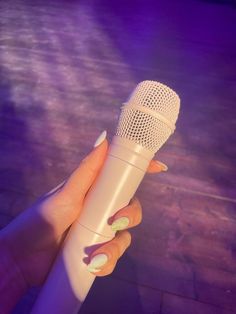 a woman's hand holding a microphone with green and white designs on the top