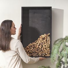 a woman is holding a large pile of wine corks in front of a blackboard