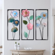 three flower paintings on the wall above a table