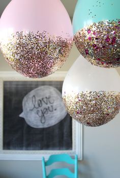 three balloons with glitter on them hanging from the ceiling