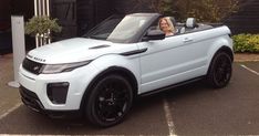 a woman is sitting in the driver's seat of a white range rover convertible