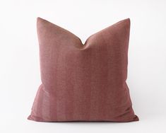 a pink pillow sitting on top of a white surface