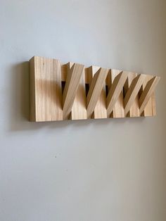 a wall mounted wooden object on the side of a wall with four different pieces of wood attached to it