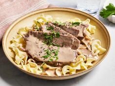 a bowl filled with meat and noodles on top of a table