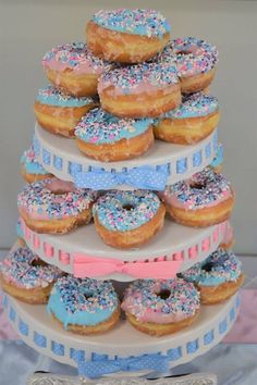 there are many donuts stacked on top of each other in this cake stand with pink, blue and white sprinkles