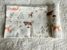 a white blanket with animals and trees on it