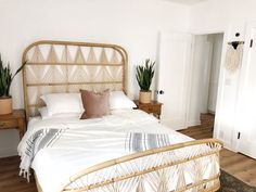 a bed with white sheets and pillows in a bedroom next to a wooden flooring