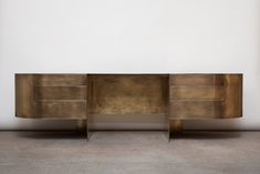 a sideboard made out of metal and wood with two shelves on each side, against a white wall