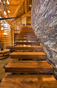 wooden steps leading up to a stone wall in a log cabin with wood flooring