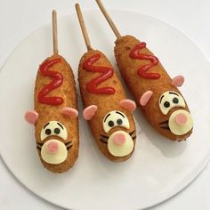 three hotdogs with ketchup and mustard on them sitting on a white plate