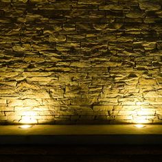 some lights that are on in front of a stone wall