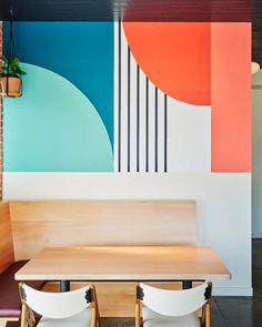 two chairs and a table in front of a colorful wall