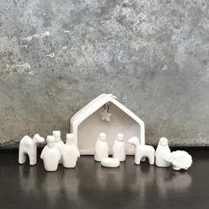 a nativity scene with white plastic figurines in front of a gray wall