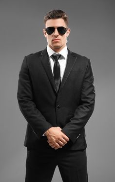 a man in a suit and sunglasses posing for the camera with his hands on his hips