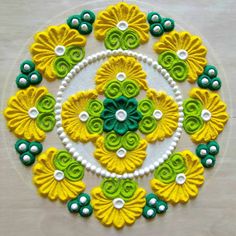 a circular design made out of yellow, green and white flowers on a white surface