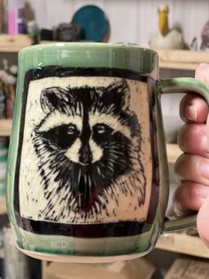 a person holding a mug with a raccoon on it