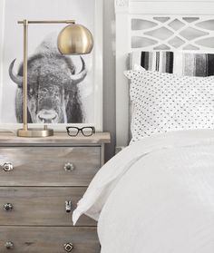 a bedroom with an animal print on the wall next to a dresser and bedding