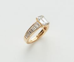 a yellow gold ring with an emerald and baguette cut diamond on the side