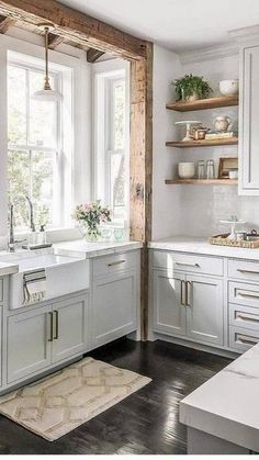 a kitchen with lots of white cabinets and counter tops in front of a large window