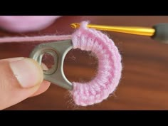 someone is crocheting the end of a piece of pink yarn with a pair of scissors