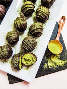 chocolate covered pastries on a white plate with green sprinkles and a spoon